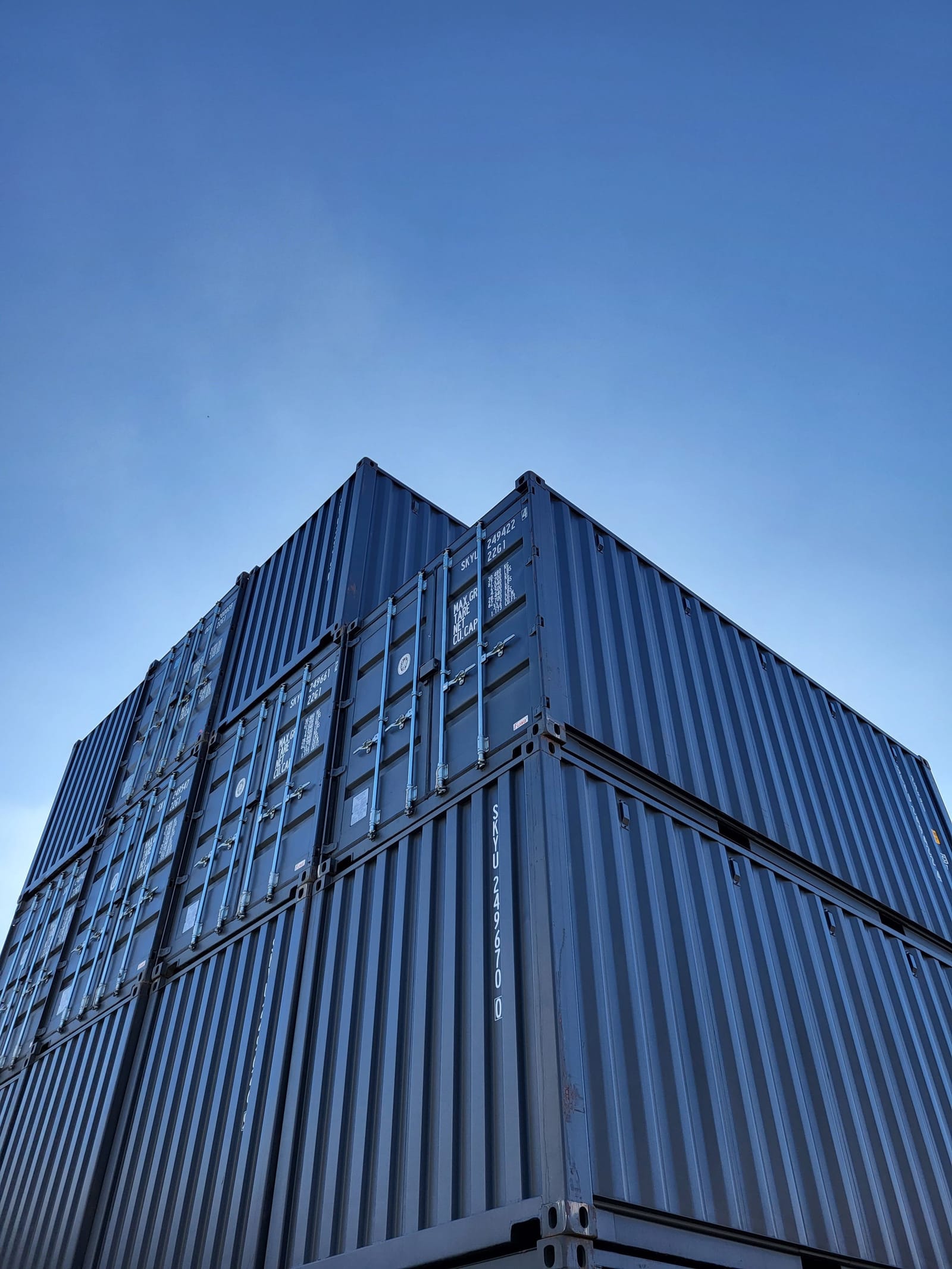 Stacked shipping containers against a clear blue sky