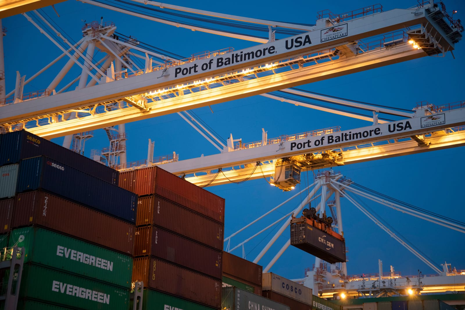 Gantry cranes at the Port of Baltimore lifting a container at dusk